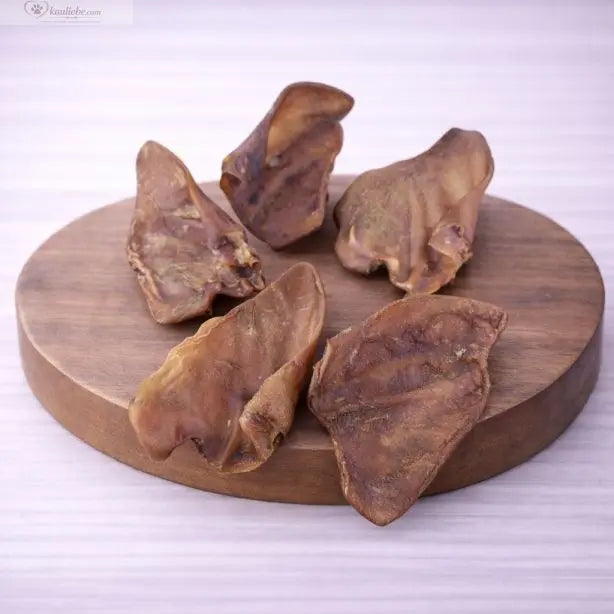 Gebackenes Schweineohr von NANDOO, saftig und knusprig, auf weißem Hintergrund, ideal als Hundeleckerli.
