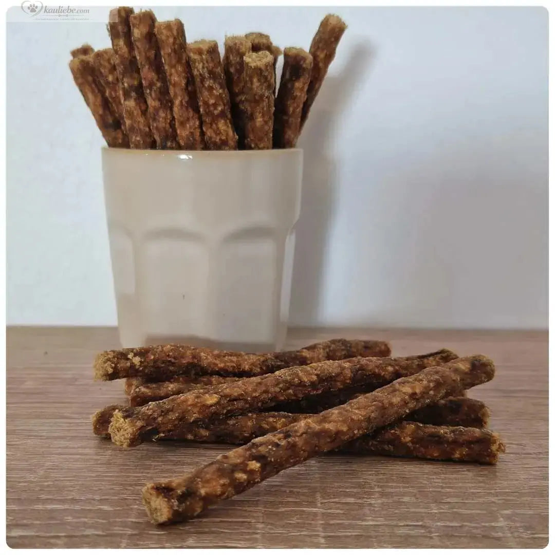 NANDOO Kaninchen Sticks 250g, getrocknete Kaninchenfleischsticks für Hunde, natürliche Hundesnacke, umgeben von getrockneten Fleischsticks