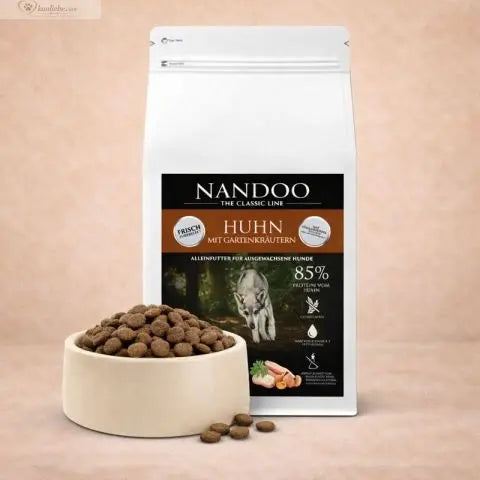 Getreidefreies Trockenfutter für Hühner mit frischen Gartenkräutern von NANDOO, in einer offenen Futterschüssel.
